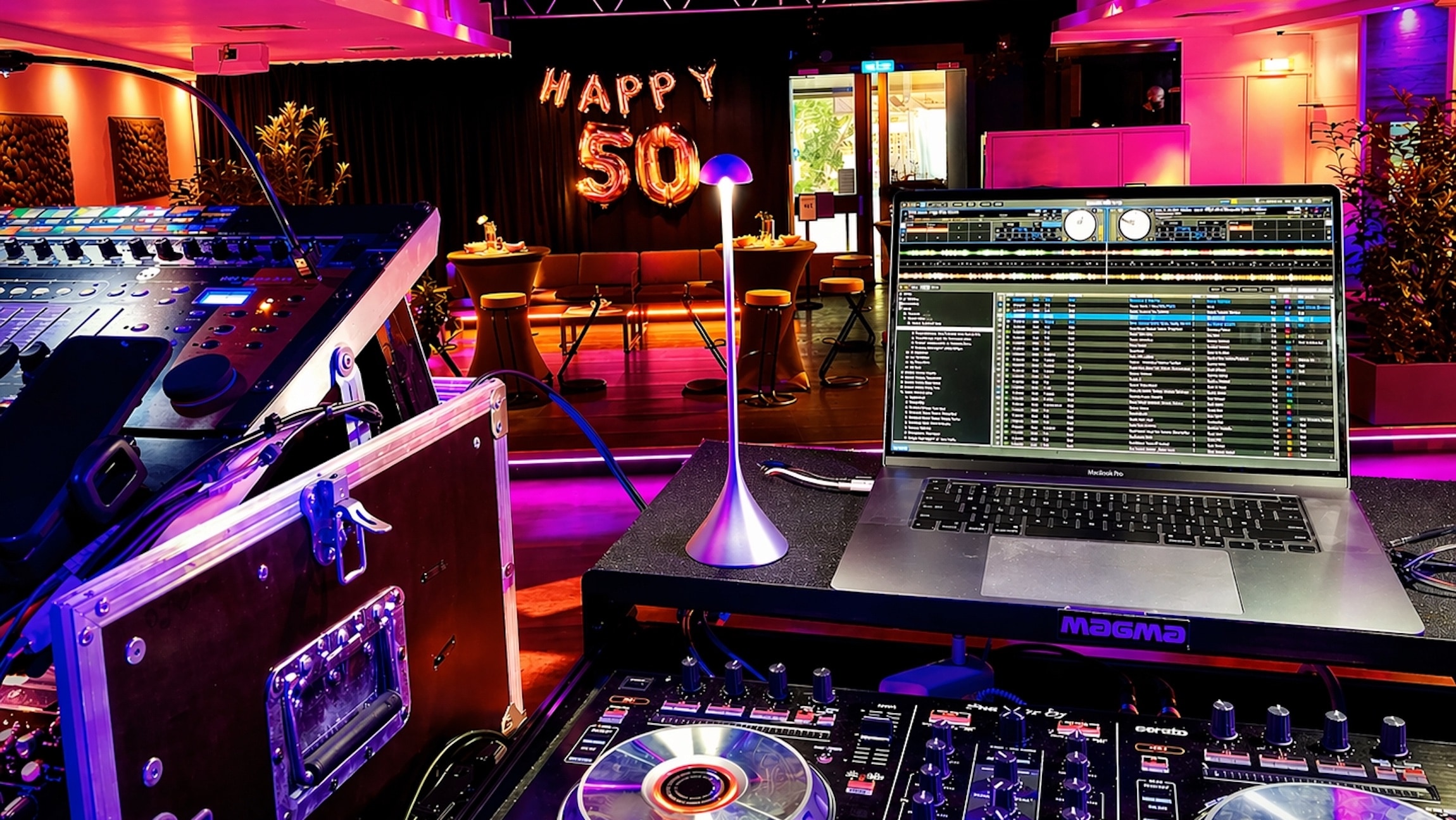Geburtstagsfeier im Saal des Oberangertheaters in München: Professionelles DJ-Equipment von Best Time DJs, ein beleuchteter DJ-Arbeitsplatz und eine farbenfrohe Partydekoration zum 50. Geburtstag mit pinkfarbener Ambientebeleuchtung.