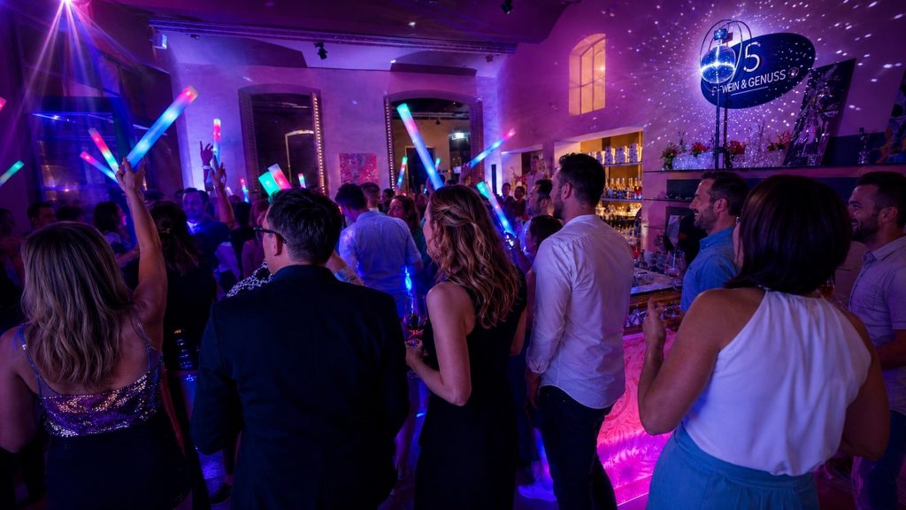 Gäste feiern zu einer Hochzeit in Kolbermoor mit bunten LED-Leuchtstäben und violetter Lichtshow auf einer Party von Best Time DJs in München.