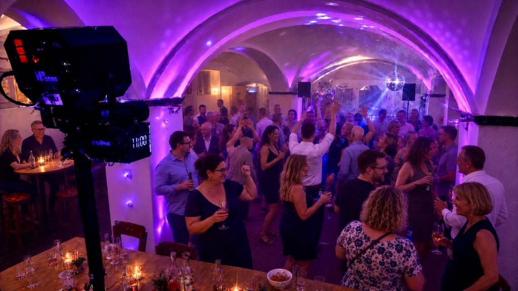Tanzende Gäste unter violetter Architekturbeleuchtung und einer Discokugel bei einer Geburtstagsfeier mit professioneller DJ-Technik.