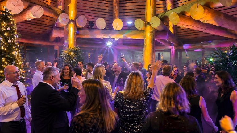 Gäste tanzen und feiern unter bunten Lichteffekten und einer Discokugel im Hafen.