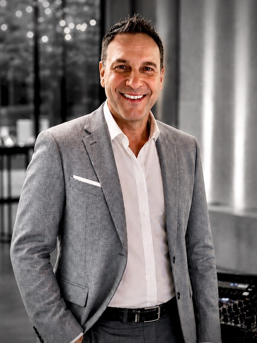 DJ Matthias von Best Time DJs aus München im eleganten grauen Sakko und weißen Hemd vor einer stilvollen Eventlocation mit DJ-Equipment zu einer Hochzeit.
