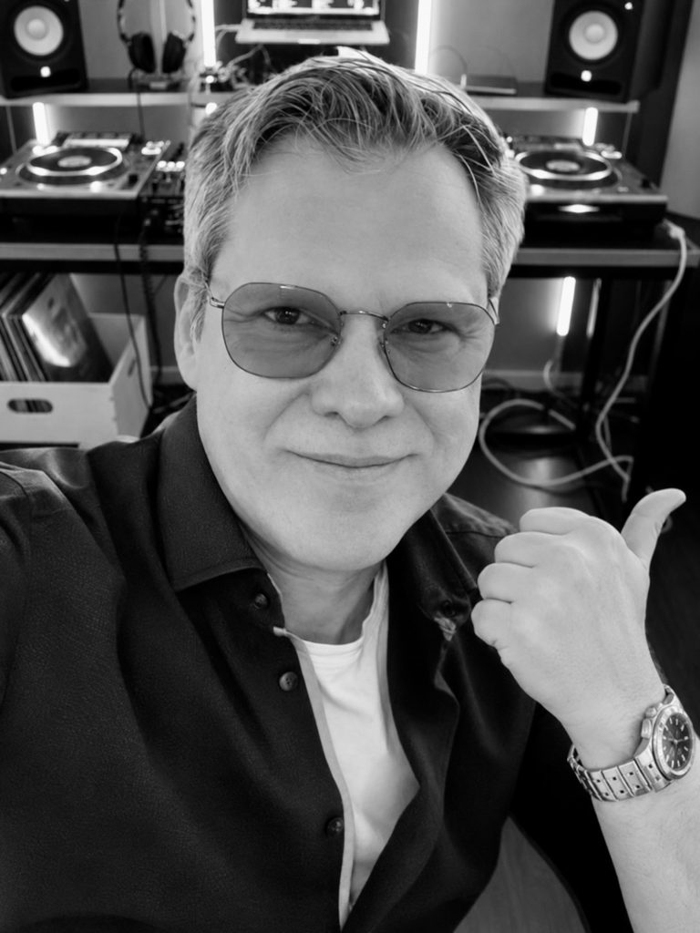 Andreas von Best Time DJs aus München zeigt im DJ-Studio lächelnd den Daumen nach links.