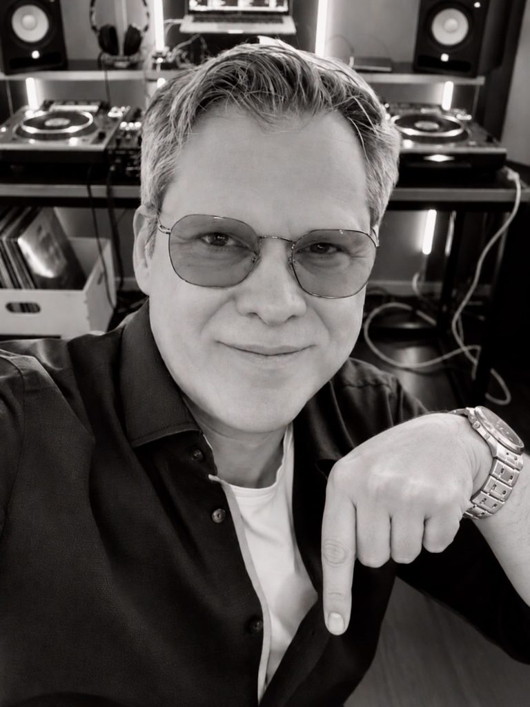 Andreas von Best Time DJs aus München zeigt im DJ-Studio mit dem Finger nach unten.